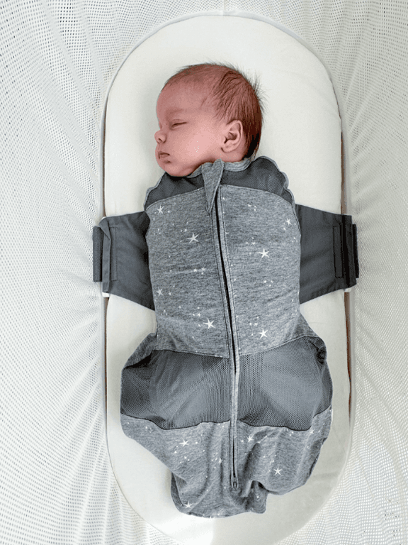 A calm baby sleeps in the Organic SNOO Sleep Sack in the SNOO bassinet