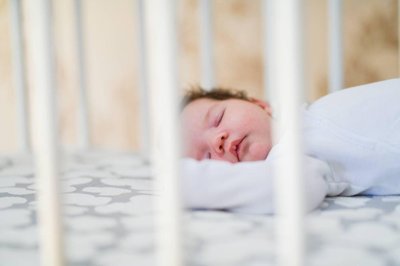 A 4-month-old baby sleeps in a cot