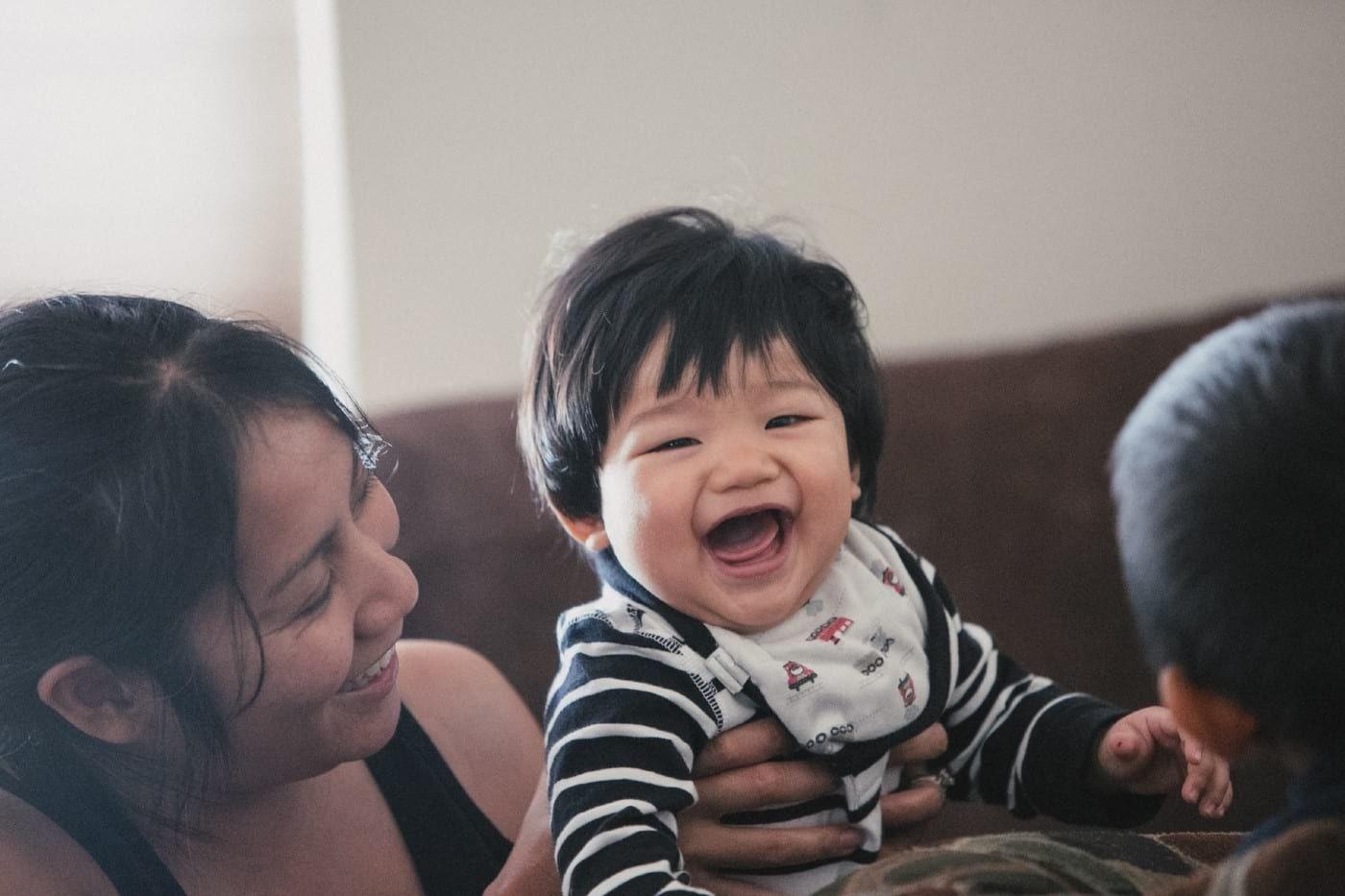 Woman smiling and holding a smiling, dark haired baby