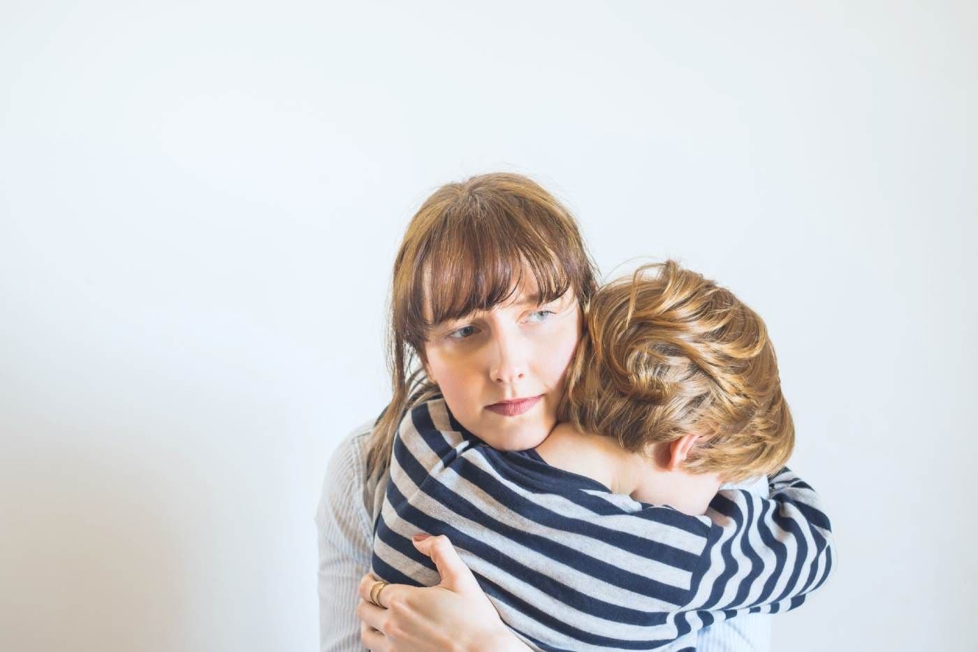 Mom holding toddler son looking pensive