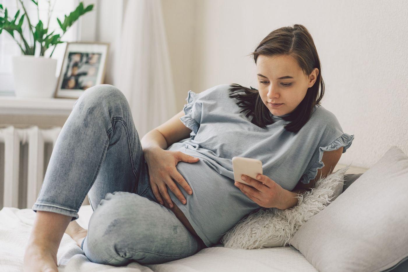 A pregnant woman looks at her phone