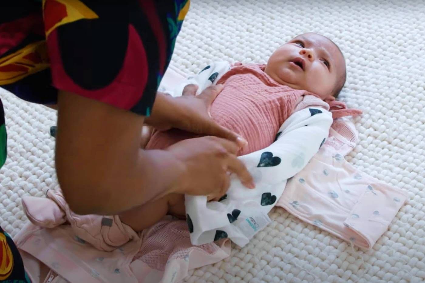 A caregiver double swaddles her baby in her SNOO Sack swaddle
