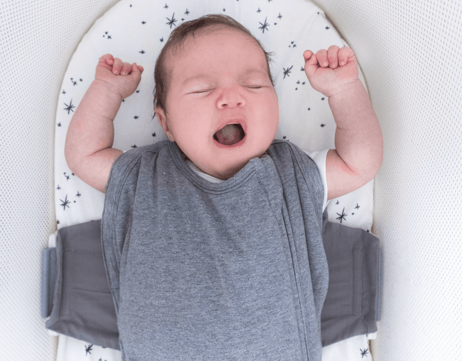 Bild av baby i SNOO-tröstpåse med armarna ut