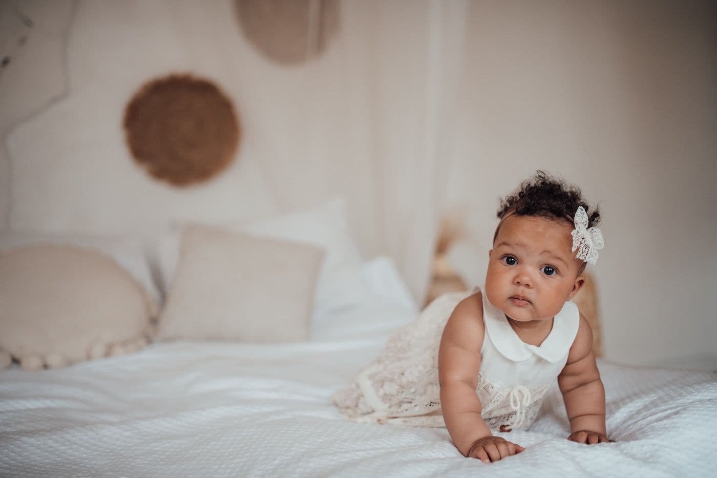 Baby dressed in white on a bed